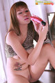 Seated with knee raised showing her shaved pussy holding vibrator.jpg