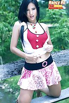 Long hair in ponytail over her shoulder pulling her top up wearing skirt kneeling on bench